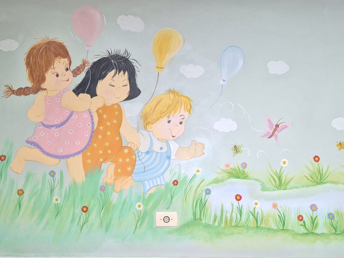 Mural pintado à mão: três crianças correndo com balões em um campo de flores e borboletas.